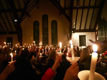 Hands holding lit candles in a dark room